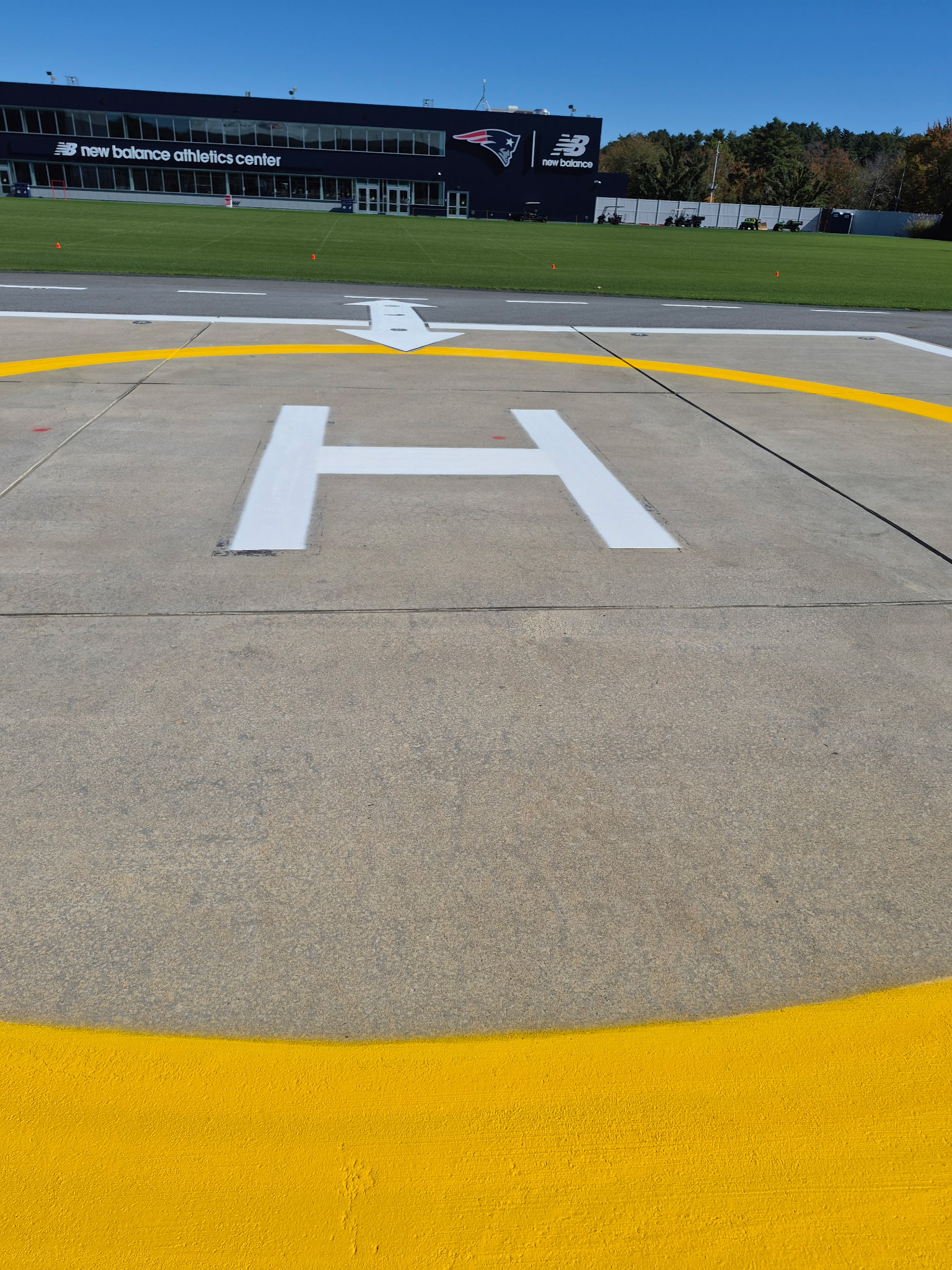 Fresh white H and yellow helipad circle with the Patriots New Balance Athletics Center in the background